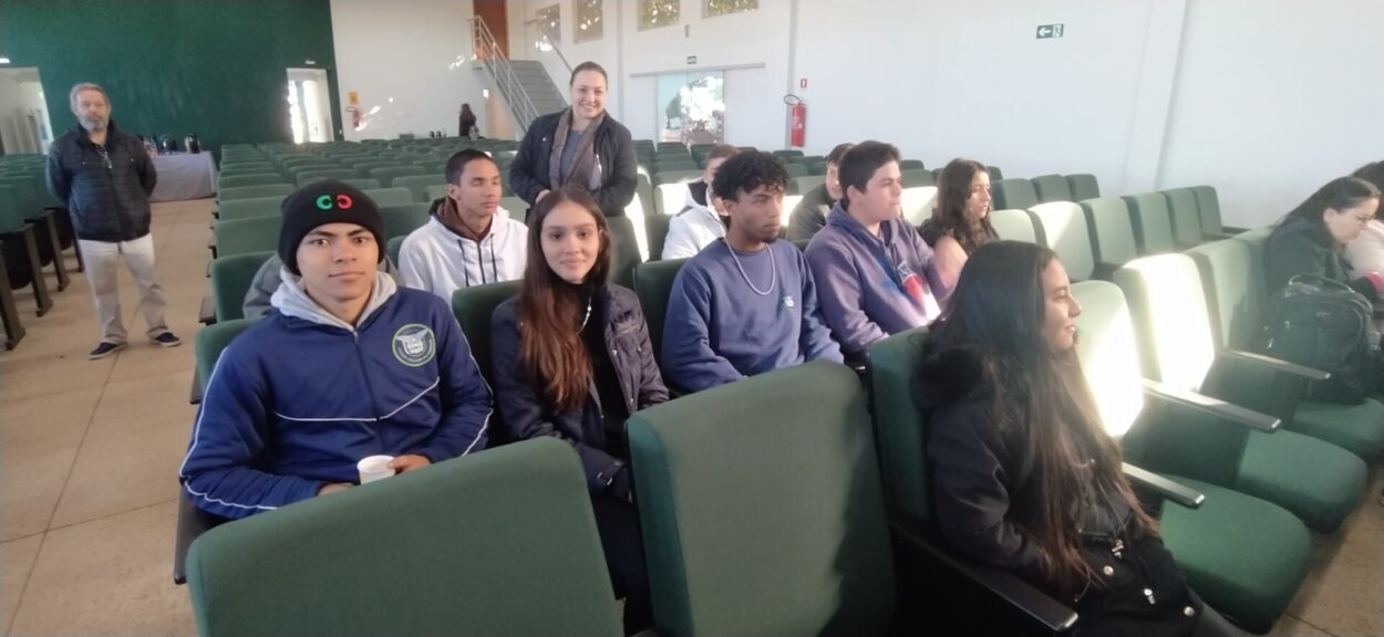 A galeria de fotos mostra 3 fotos com alguns momentos do Seminário Mudanças Climáticas e COP30: os alunos do clube de ciências e professores posando para uma foto em frente a um painel com o logo do seminário; o palestrante Atila Iamarino falando ao público; uma foto dos alunos sentados no auditório.