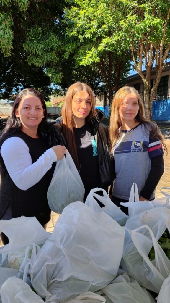 A galeria mostra fotos dos clubistas entregando as alfaces que eles cultivaram aos pais e alunos da escola. Há ambientes internos e externos e as alfaces estão envolvidas em sacolas plásticas para a praticidade no transporte. Alguns adultos são pais dos alunos e seguram pacotes contendo uniformes escolares.