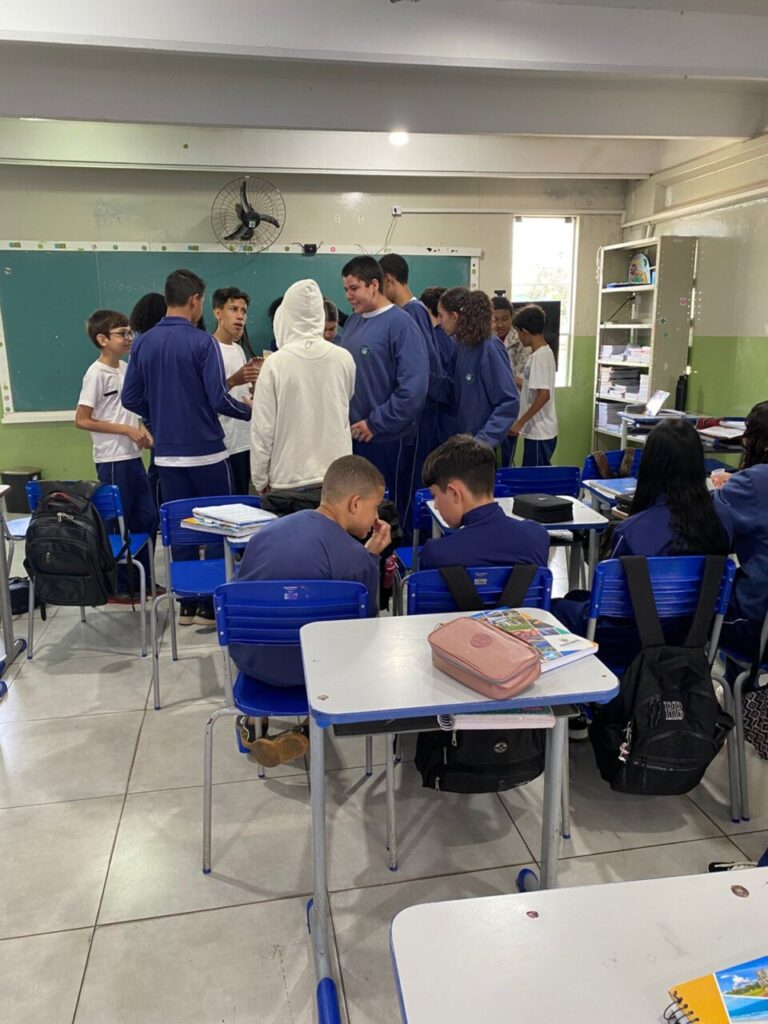A galeria de fotos mostra momentos da apresentação e degustação do energético produzido pelo clube de ciências Ciência na Mesa. As imagens mostram estudantes na sala de aula com as mesas organizadas para oferecer o energético em copo descartáveis. Todos parecem felizes, sorrindo e curiosos com a proposta de bebida alternativa