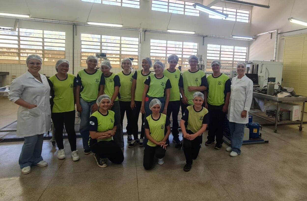 Na primeira fotografia é possível ver um grupo de pessoas posando juntas dentro de uma sala de aula. Ao todo, são dez pessoas: oito jovens e dois adultos. Eles estão posicionados lado a lado. O ambiente é típico de sala de aula, com paredes amarelas, quadro verde ao fundo e piso de cerâmica. A segunda imagem é do Clube Ilha da Ciência. A imagem mostra um grupo de estudantes e duas mulheres posando em um ambiente ao ar livre, com árvores, arbustos e canteiros de horta ao fundo. O grupo está sorridente, alguns em pé e outros agachados na frente. Na terceira fotografia tem um grupo de estudantes reunidos em um ambiente escolar ao ar livre, em frente a um jardim vertical com diversas plantas verdes. Eles estão distribuídos em pé e agachados, posando para a foto. A quarta imagem mostra um grupo de estudantes e um adulto reunidos em um espaço ao ar livre, posando para uma foto em frente a uma grande escultura de uma figura humana com os braços abertos. O grupo está distribuído sobre um pequeno morro coberto de grama, alguns sentados e outros em pé. A quinta imagem é do Clube Experimentando a Ciência: Descobrindo cores e novos sabores. A imagem mostra um grupo de estudantes e professores posando para uma foto ao ar livre, em frente a uma placa de madeira com o desenho de uma abelha e a palavra “Meliponário”. Estão sorridentes e organizados ao redor da placa. Na sexta imagem mostra um grupo grande de pessoas, formado por adolescentes e um adulto, posando para uma foto em uma sala. Eles estão organizados em duas fileiras: alguns sentados ou agachados na frente. A sala tem paredes claras, ventiladores fixados na parede e um quadro branco ao fundo. À esquerda, há uma mesa com uma toalha vermelha e alguns objetos decorativos para um evento escolar. A última fotografia tem um grupo de estudantes e alguns adultos reunidos para uma foto em um ambiente escolar externo. Eles estão em frente a uma parede branca com detalhes verdes e uma janela comprida com grades. O grupo está posicionado em duas fileiras, com alguns agachados na frente e outros em pé atrás, todos sorrindo.