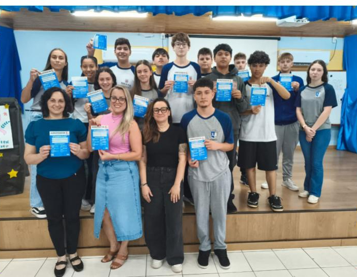 A galeria registra momentos da Culminância do Colégio Estadual Guilherme de Almeida, em Santa Izabel do Oeste (PR). Em um auditório com carteiras enfileiradas, palco, cortinas e projetor, professores e clubistas apresentam os projetos desenvolvidos ao longo do ano de 2025. Há, ainda, imagens de um panfleto intitulado 'Agrotóxicos e o Câncer de Mama' e outros momentos marcantes do clube.