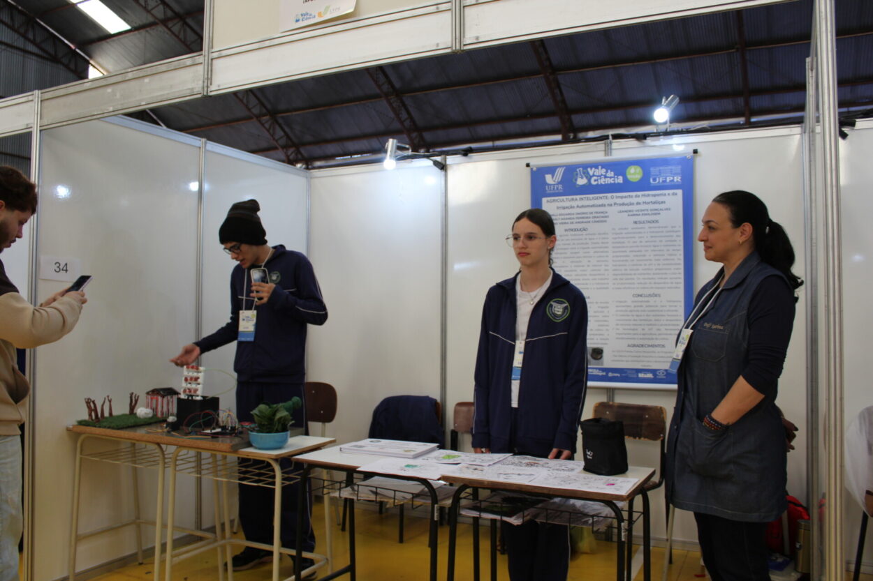A galeria reúne momentos do 6º Vale da Ciência, feira promovida pela Universidade Federal do Paraná (UFPR) por meio do Câmpus Avançado de Jandaia do Sul. As imagens registram os estandes dos projetos dos clubes de ciências e seus autores em um pavilhão amplo, caracterizado por sua estrutura metálica aparente e pela iluminação natural que entra pelas laterais superiores.