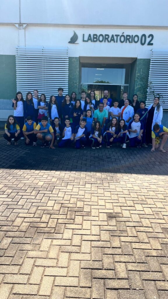 A galeria registra os momentos da visita do clube ao campus da UFFS Realeza. As imagens externas destacam a área verde da universidade e os estudantes acompanhados pelo coordenador do projeto durante a visita guiada. Já os registros internos apresentam as atividades práticas realizadas no laboratório, onde os alunos participaram da oficina.