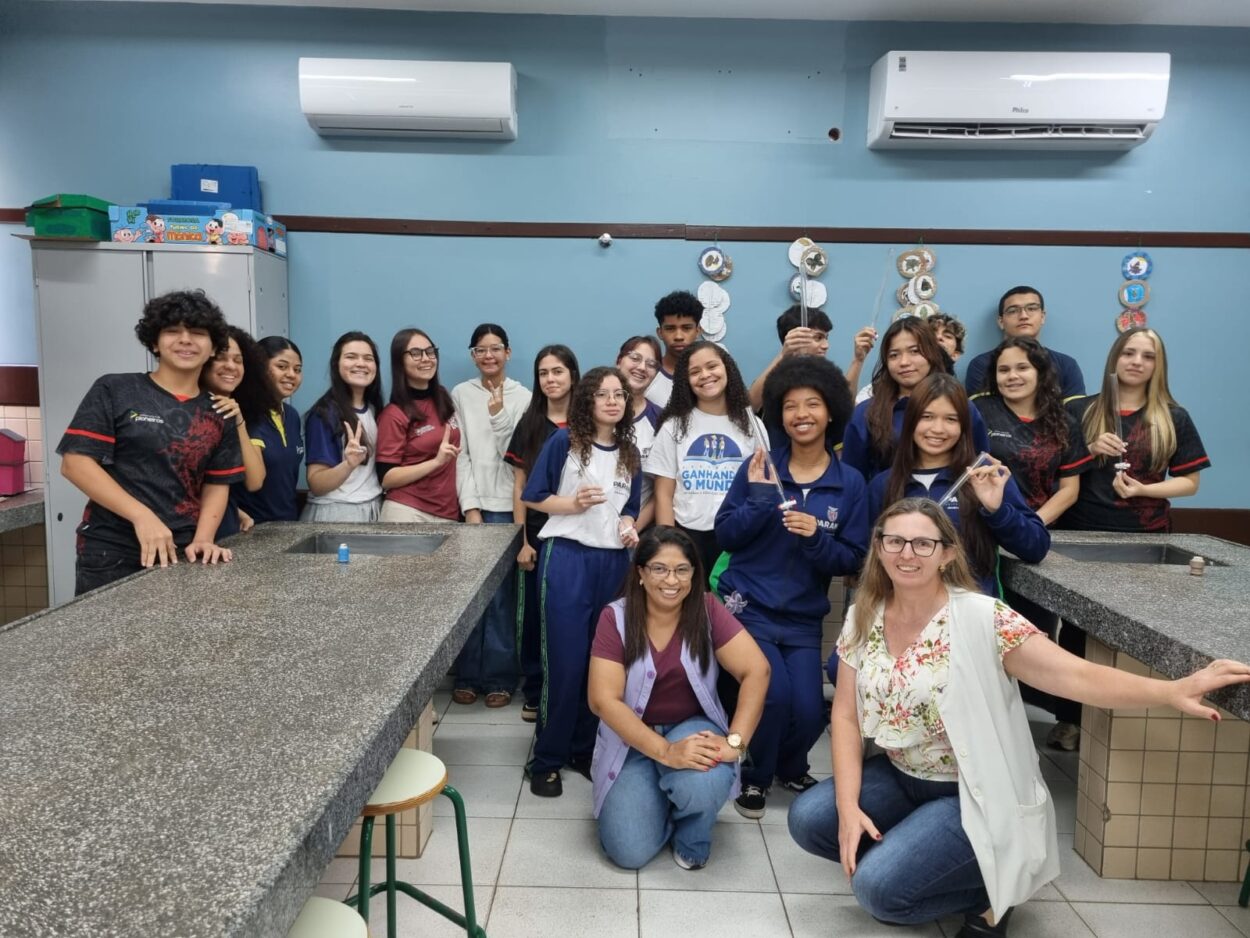 Alunos do clube de ciências InterAção reunidos no laboratório do clube, vestidos de jalecos brancos.
