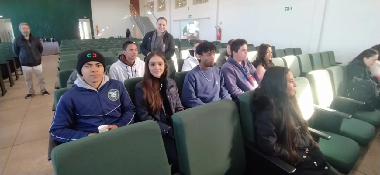 A galeria de fotos mostra 3 fotos com alguns momentos do Seminário Mudanças Climáticas e COP30: os alunos do clube de ciências e professores posando para uma foto em frente a um painel com o logo do seminário; o palestrante Atila Iamarino falando ao público; uma foto dos alunos sentados no auditório.