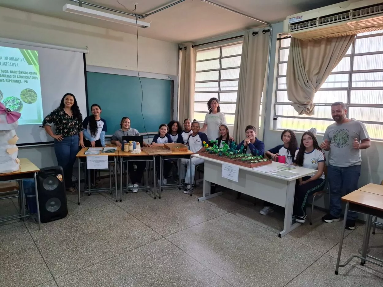 Na foto, um grupo de estudantes e professores posam em sala de aula durante a 1ª Feira de Ciências da Unespar – campus Paranavaí. Eles estão reunidos ao redor de duas mesas que expõem projetos científicos.