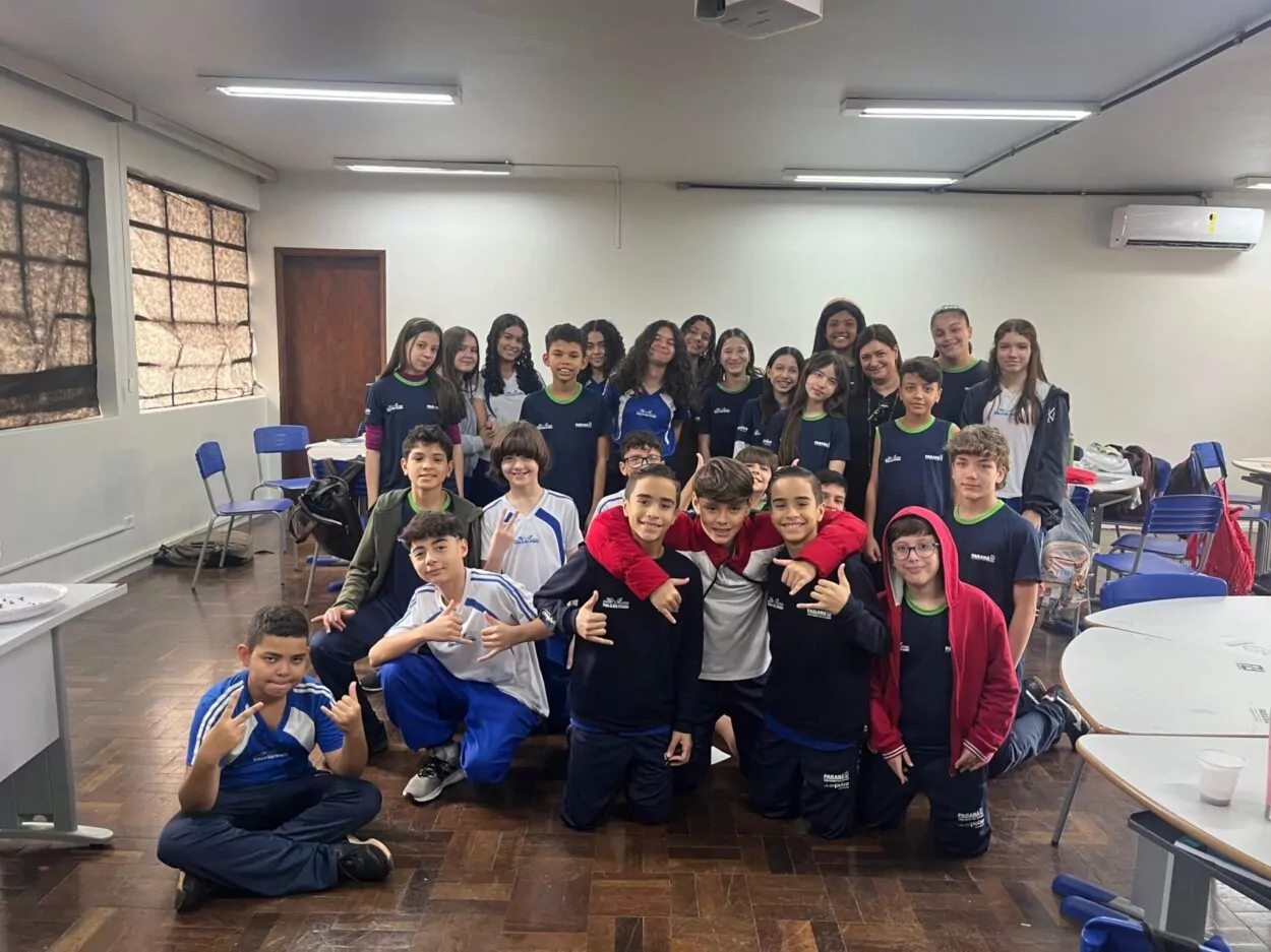 A primeira foto é do Clube de Ciências ‘Cienteens’ do Colégio Instituto de Educação Estadual de Maringá. Na imagem, vemos um grupo de onze pessoas posando dentro de uma sala de aula. A maioria são jovens estudantes, acompanhados por uma mulher adulta, que é a professora, posicionada no centro da foto. Na segunda fotografia há um grupo de seis pessoas do Clube ‘Capivara´s Tech’, estudantes e uma professora, posando sorridentes em frente a um painel que diz "Clube de Ciências - Capivara’s Tech". Eles estão sentados em bancos e mesas. Há pequenos vasos de planta como decoração. A terceira imagem mostra um grupo de estudantes do Clube Paulo Sérgio Bretones em uma sala de aula. São aproximadamente 30 pessoas, sendo alunos e professora. O ambiente é uma sala de aula com mesas redondas, cadeiras azuis e um piso de madeira escura. Há um ar-condicionado fixado na parede ao fundo e luminárias no teto. Algumas mochilas e materiais escolares estão ao redor da sala. A quarta foto tem um grupo de alunos apresentando um projeto do Clube ‘Robótica e Sustentabilidade, Solidariedade em Ação’ em uma sala decorada com folhas verdes penduradas. Na frente da mesa, há cartazes escritos e materiais como garrafas PET e experimentos.